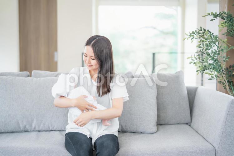 ソファーで赤ちゃんを抱っこする女性 赤ちゃん,ママ,お母さんの写真素材