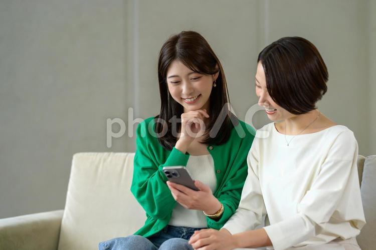 ソファに座って笑い合う日本人女性 おしゃべり,リビング,友達の写真素材