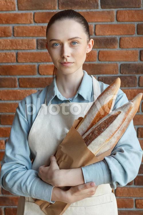 真顔で紙袋のパンを持つ女性 女性,パン,バゲットの写真素材