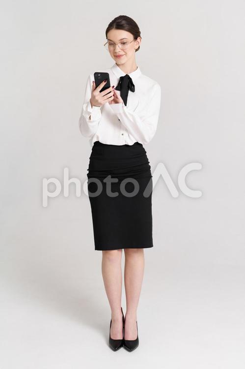 微笑みスマホを操作するメガネ女性 女性,スマートフォン,持つの写真素材