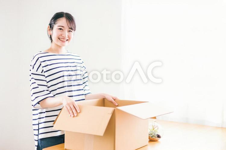 段ボールを笑顔で開ける女性（通販・宅配） 通販,新生活,大学生の写真素材