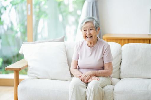 リビングのソファに座り笑う女性 女性,笑顔,ソファの写真素材