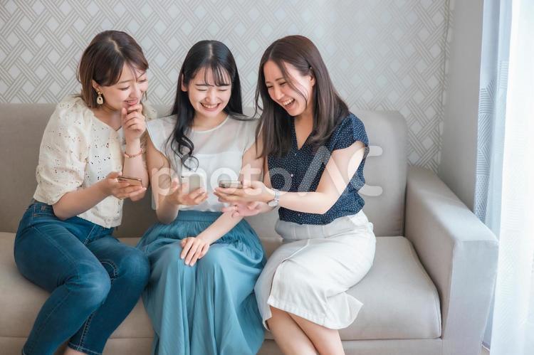 スマホを使う女性たち（爆笑） スマートフォン,スマホ,女子会の写真素材
