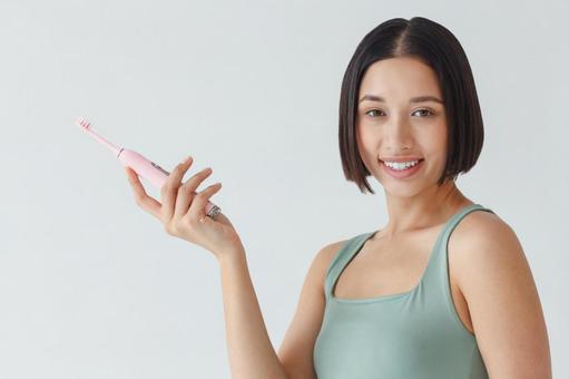 電動歯ブラシを持って振り向く女性 電動歯ブラシを持って振り向く女性 女性,歯ブラシ,振り向くの写真素材