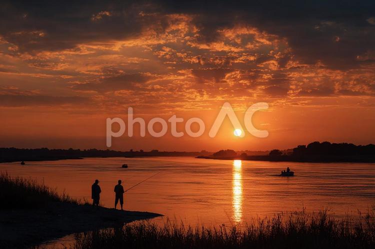 燃えるような空の下静かに佇むボートと人々 夕焼け,夕日,日没の写真素材
