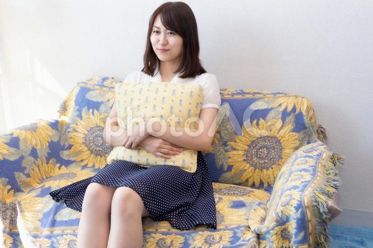 ソファーに座りクッションを抱きかかえている女性 女性,ol,顔の写真素材