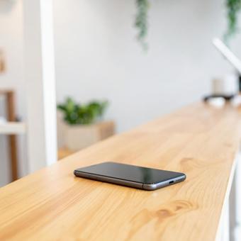 木製カウンターに置かれたスマートフォンの写真