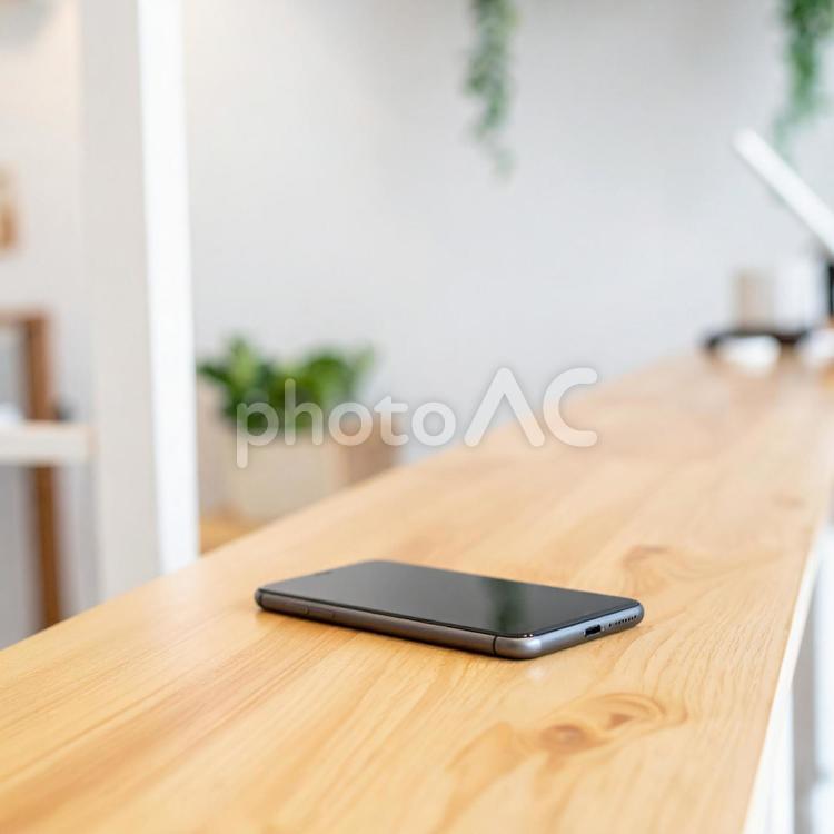 木製カウンターに置かれたスマートフォン スマートフォン,スマホ,携帯電話の写真素材