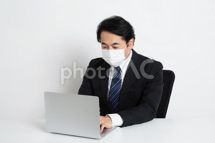 マスクをしながら仕事をしている中年のサラリーマン男性 中年,上司,会社員の写真素材