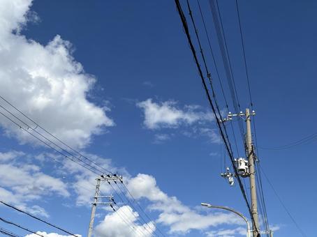 秋晴れに伸びる電線の写真