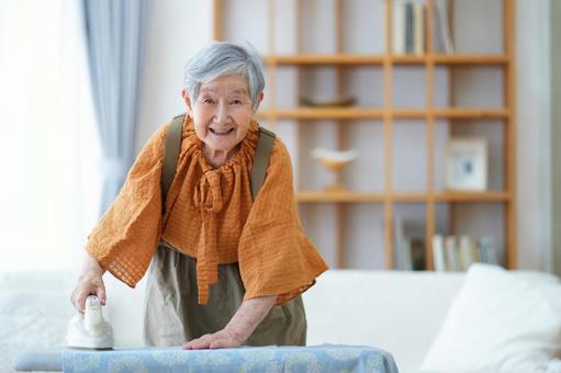 笑顔でアイロン掛けをするおばあちゃん 女性,アイロン,アイロン台の写真素材