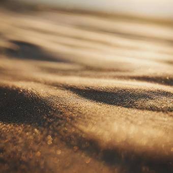 キラキラと光る、夕焼けに染まる砂浜の写真