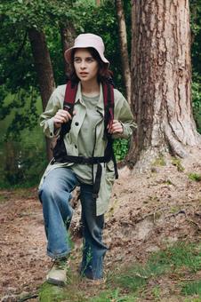 森の中でリュックを背負い立つ女性の写真