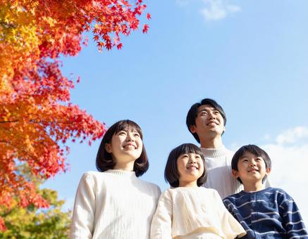 青空の下で秋の紅葉を仲良く鑑賞する家族 青空の下で秋の紅葉を仲良く鑑賞する家族の写真