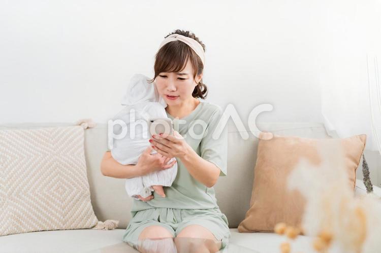 赤ちゃんを抱っこしながらスマホを使う女性 赤ちゃん,育児,困るの写真素材