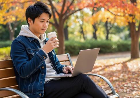 秋の公園でリモートワークする男性 秋の公園でリモートワークする男性の写真