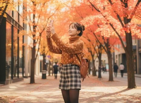 スマフォで紅葉を撮影する若い女性 スマフォで紅葉を撮影する若い女性の写真