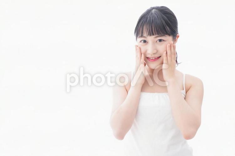 フェイシャルケアをする若い女性 白バック,思春期,塗るの写真素材