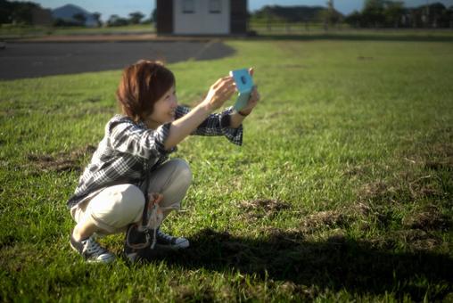＜素材＞夜明けの観光地で写真を撮る女性 女性,スマホ,笑顔の写真素材