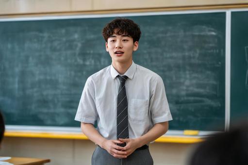 黒板の前で発表する男子生徒のイメージの写真
