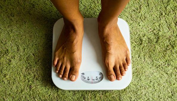 白い体重計に足を乗せる若い女性の写真