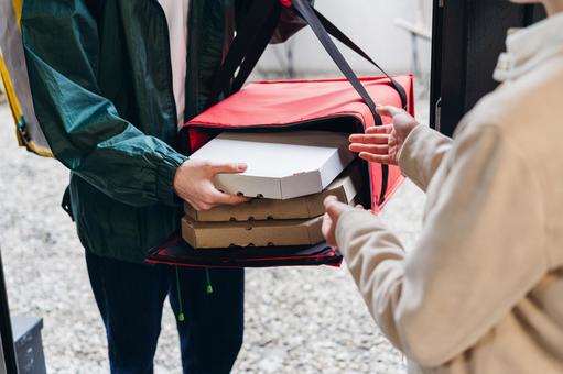 保温ピザバッグからピザを出している男性 配達,フードデリバリー,デリバリーの写真素材