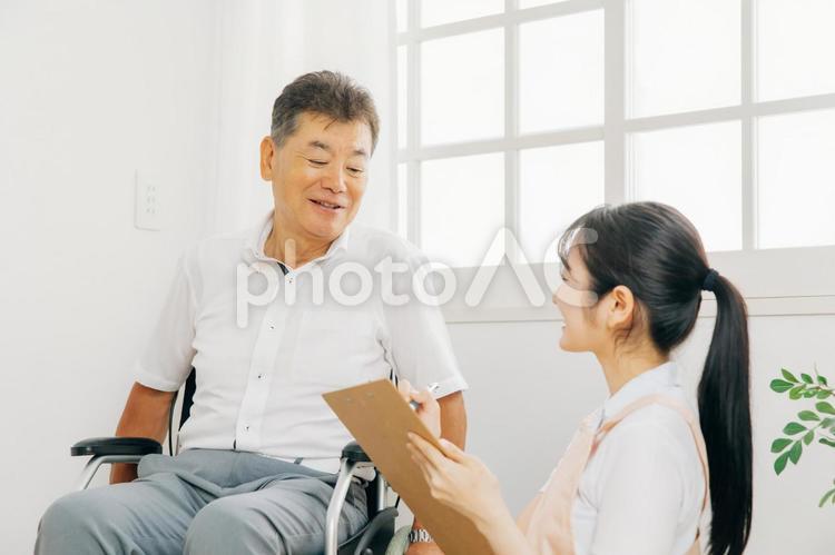 高齢者男性と話す介護士（メモ） ケアマネジャー,高齢者,介護士の写真素材