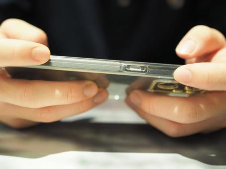The hand of a young man holding a smartphone sideways, JPG