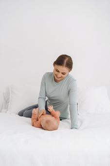 仰向けの赤ちゃんをあやしている女性 仰向けの赤ちゃんをあやしている女性 親子,仰向け,ベッドの写真素材