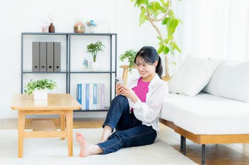 部屋でスマホを操作する若い女性 部屋でスマホを操作する若い女性 スマホ,笑顔,女性の写真素材