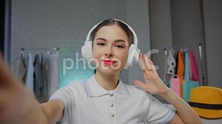 ヘッドフォンを押さえて微笑む女性 女性,人物,インフルエンサーの写真素材