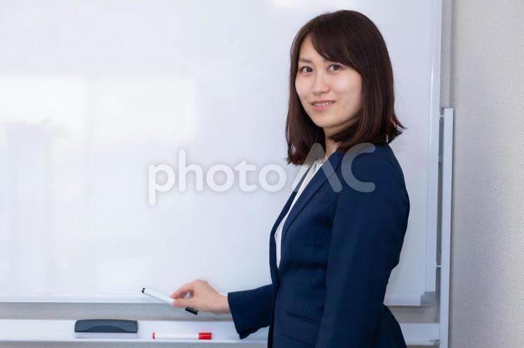 ホワイトボードを使おうとしているスーツの女性 女性,スーツ,ホワイトボードの写真素材