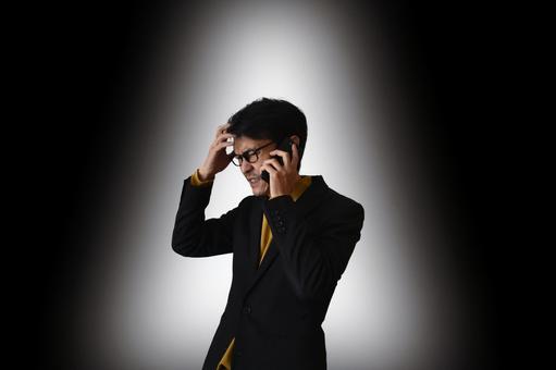 通話しながら不機嫌な男性 通話,スマホ,トラブルの写真素材