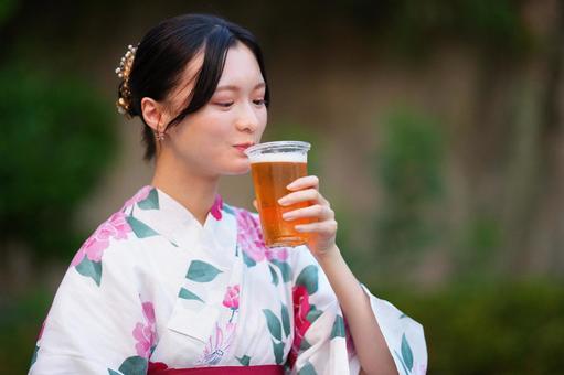 浴衣姿の女性がドリンクを片手に微笑むの写真