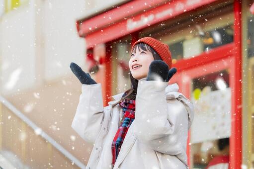 雪の降る冬の街角に立つ笑顔の女性 冬,雪,女性の写真素材