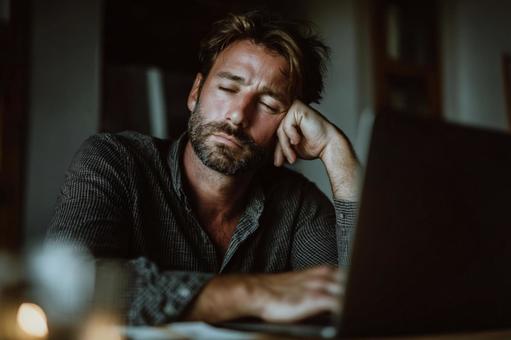 パソコンの前で居眠りする疲れた中年男性 パソコンの前で居眠りする疲れた中年男性の写真