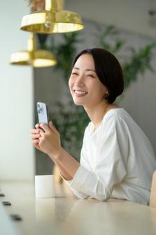 カフェでスマホを操作する日本人女性 カフェでスマホを操作する日本人女性の写真