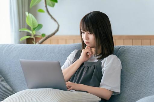 ソファに座ってパソコンを使う女性 女性,ソファ,パソコンの写真素材