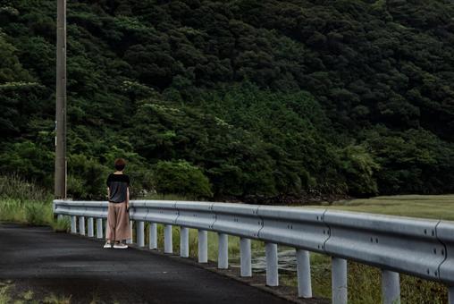 ＜素材＞雨上がり田舎の川沿いを歩く女性 女性,悩む,雨上がりの写真素材