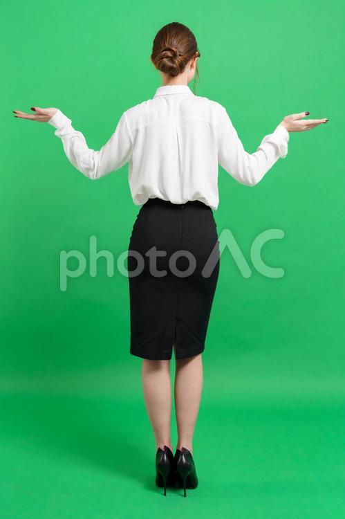 お手上げポーズ女性の後ろ姿（緑背景） 後ろ姿,立つ,ポーズの写真素材