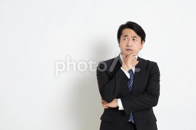 アゴに手をあて悩んでいる中年のサラリーマン男性（コピースペース） 中年,上司,会社員の写真素材