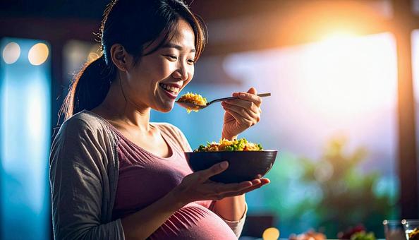 食事を美味しそうに食べる妊婦 食事を美味しそうに食べる妊婦の写真
