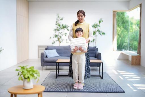 畳まれたタオルを持つ女の子と母 畳まれたタオルを持つ女の子と母 娘,母,洗濯物の写真素材