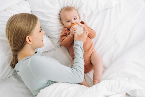 ベッドでミルクを飲ませている母 ベッドでミルクを飲ませている母 親子,赤ちゃん,哺乳瓶の写真素材
