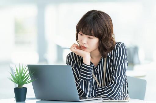 パソコンを使いながら考える女性 女性,パソコン,考えるの写真素材