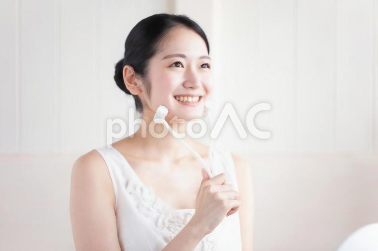美顔ローラーを使う女性（笑顔） 美顔ローラー,ローラー,顔痩せの写真素材