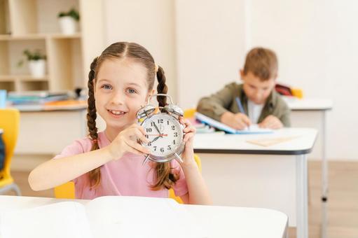 時計を見せる女の子の後ろで真剣にノートに書く男の子 男の子,女の子,子どもの写真素材