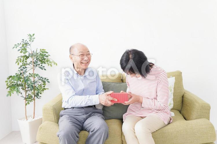プレゼントを渡す高齢の夫婦 年金,医療費,手渡しの写真素材