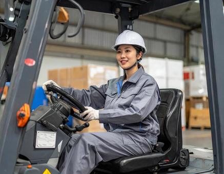 フォークリフトを運転する女性作業員の写真