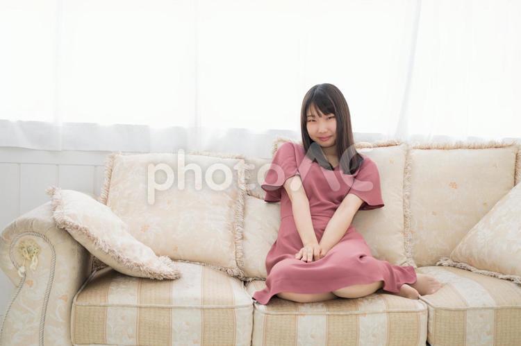 ソファーの上に座って微笑む２０代の女性 笑顔,女性,人物の写真素材
